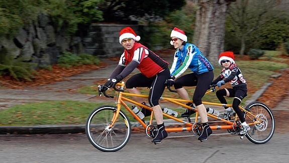 Orange 3 bicycle built for 3 with family riding it