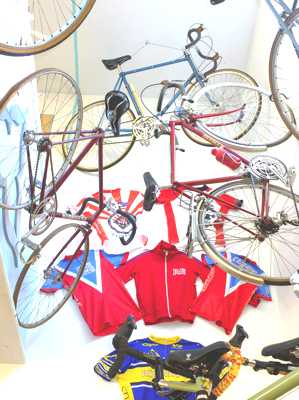 Looking up at 3 of the vintage Rodriguez bikes in the new museum with the wall of Jerseys behind it